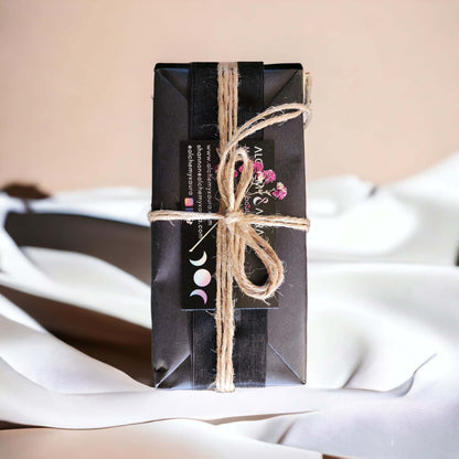 Luxury candle gift set by Alchemy & Aura wrapped with natural twine in black kraft paper. Top view with dried flowers.